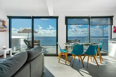 a living room with a couch and a table with chairs at The Wave House - Two Bedroom Flat in Jardim do Mar