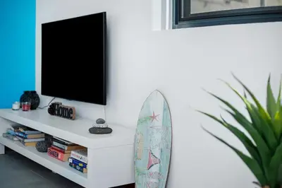 a surfboard leaning against a wall with a tv at The Wave House - Two Bedroom Flat in Jardim do Mar