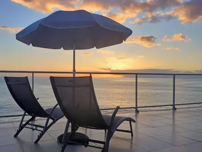 a patio with a table and an umbrella and a chair at The Wave House - Two Bedroom Flat in Jardim do Mar
