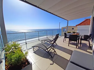 a balcony with chairs and a table and the ocean at The Wave House - Two Bedroom Flat in Jardim do Mar