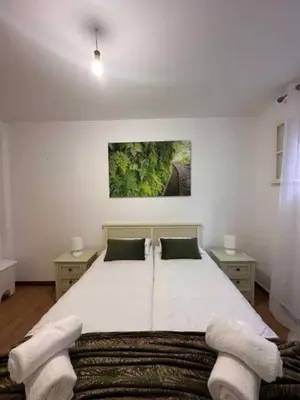 a bedroom with a large white bed with two chairs at Casa Valhalla in Funchal