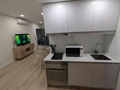 a kitchen with white cabinets and a sink and a microwave at Top-Floor One-Bedroom Flats - Peaceful with Ocean and City Views in Funchal