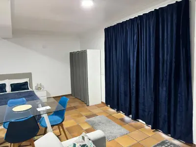 a bedroom with a blue curtain and a table and chairs at Alforra Residence 2-Centro-Praias-Levadas in Câmara de Lobos