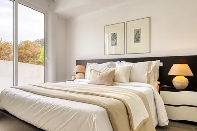 a white bedroom with a large bed and a window at Ribas Machico, a Home in Madeira in Machico