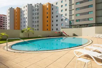 a large swimming pool with chairs and some buildings at Fantástico apartamento na zona nobre - Bella Vita in Funchal