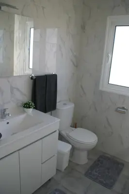 a white bathroom with a toilet and a sink at Casa do Prendinha B in Ponta do Pargo