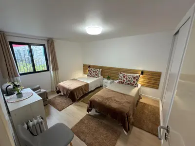 a room with two beds and a table and a chair at Vivenda Silva in Seixal