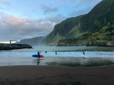 a person standing on the beach with a surfboard at Vivenda Silva in Seixal