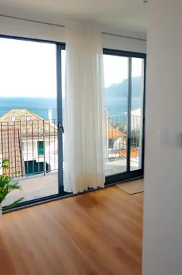 a room with sliding glass doors with a view of the ocean at Vivenda Silva in Seixal