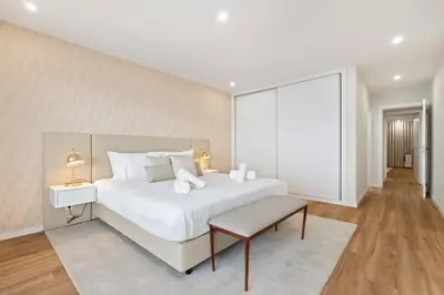a white bedroom with a large bed and a table at Sunset Vista 604 in Funchal
