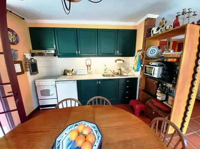 a kitchen with green cabinets and a wooden table at Casa da Lagoa BB or HB options in Santana