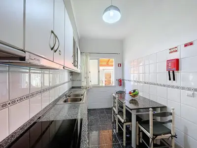 a white kitchen with a table and a sink at Eddys House by Atlantic Holiday in Água de Pena