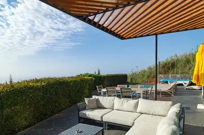 a patio with a couch and tables and a pool at Villa Eden Sky in Prazeres in Prazeres