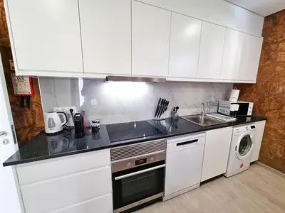a kitchen with white cabinets and a sink and a dishwasher at Casa Caromba, Sunrise in Prazeres