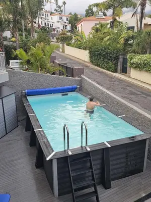 a man in a swimming pool with chairs and a table at RODRIGUES ViLLA in Funchal