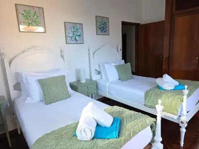 a bedroom with two white beds and a night stand at RODRIGUES ViLLA in Funchal