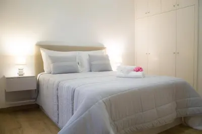 a white bed with white sheets and a pink stuffed animal on it at Casa Caromba, Sunset in Prazeres