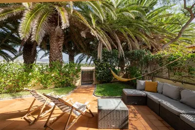 a patio with a couch and chairs and palm trees at Casa do Ribeiro Salgado II by An Island Apart in Porto Santo