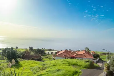 a house on a hill with the ocean in the background at Villa Eden Nature in Prazeres in Prazeres