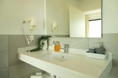 a white bathroom with a sink and a mirror at Villa Eden Nature in Prazeres in Prazeres