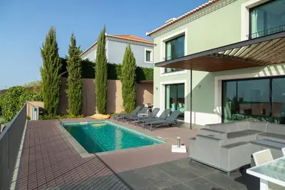 a swimming pool with chairs and a house at Villa Eden Nature in Prazeres in Prazeres