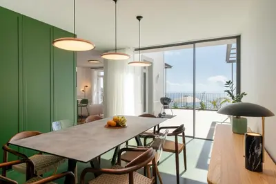 a dining room with a table and chairs and a green wall at MemorHia Village by OurMadeira in Calheta