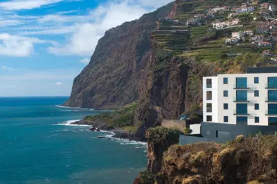 a building on a cliff next to the ocean at Atlantic Heights Varandas do Atlântico by Holiday Rental Madeira in Câmara de Lobos
