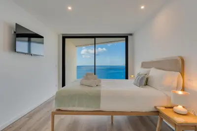 a bedroom with a bed with a view of the ocean at Atlantic Heights Varandas do Atlântico by Holiday Rental Madeira in Câmara de Lobos