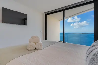 a bedroom with a bed with a large window at Atlantic Heights Varandas do Atlântico by Holiday Rental Madeira in Câmara de Lobos