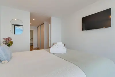 a bedroom with a large white bed with a flat screen tv at Atlantic Heights Varandas do Atlântico by Holiday Rental Madeira in Câmara de Lobos