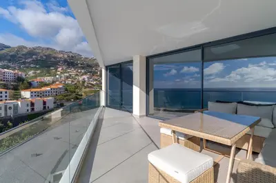 a balcony of a house with a table and chairs at Atlantic Heights Varandas do Atlântico by Holiday Rental Madeira in Câmara de Lobos