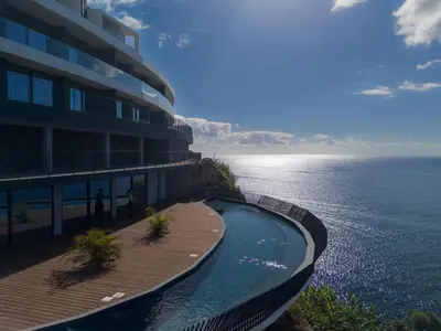 a building with a swimming pool next to the ocean at Atlantic Heights Varandas do Atlântico by Holiday Rental Madeira in Câmara de Lobos