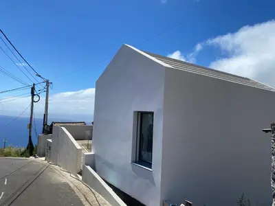 a white building with a window on a street at Villa MARIE in Fajã da Ovelha