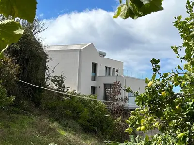 a white building on the side of a hill at Villa MARIE in Fajã da Ovelha