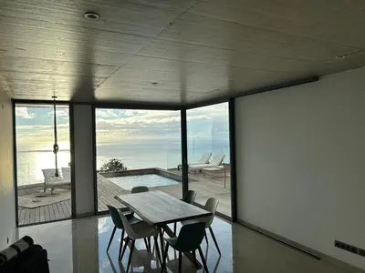 a dining room with a table and chairs and a pool at Villa MARIE in Fajã da Ovelha