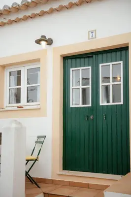 a green garage door on a house with two windows at Casa Roma in Raposeira