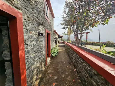 a stone building with a wall next to a sidewalk at Refugio Jardim Prazeres WiFi BBQ in Prazeres