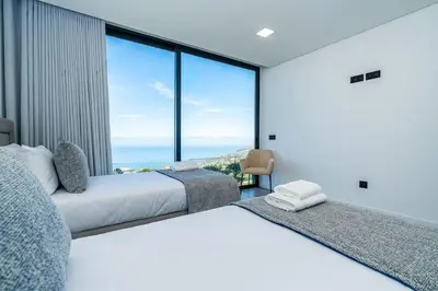 two beds in a room with a view of the ocean at Villa Lunarenzo seaview, Pool, AC, parking in Calheta