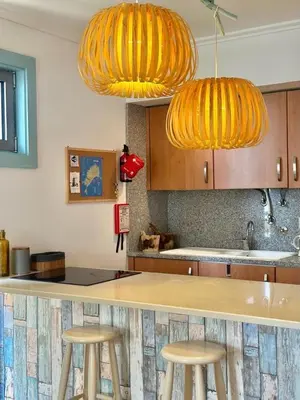 a kitchen with three bar stools and two lights at Casa Bamboo in Porto Santo