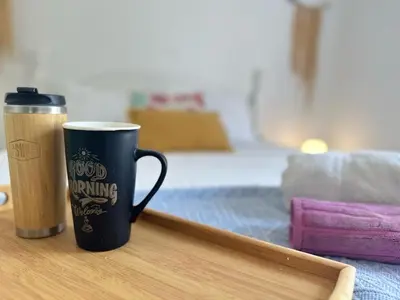 a coffee cup sitting on a table next to a bed at Casa Bamboo in Porto Santo