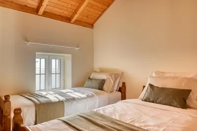 two beds in a room with a window at Ocean View Cottage a Home in Madeira in Fajã da Ovelha