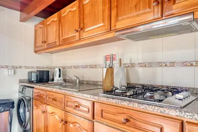a kitchen with wooden cabinets and a stove top oven at Ocean View Cottage a Home in Madeira in Fajã da Ovelha