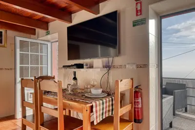 a dining room with a table and a flat screen tv at Ocean View Cottage a Home in Madeira in Fajã da Ovelha