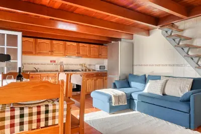 a living room with a blue couch and a kitchen at Ocean View Cottage a Home in Madeira in Fajã da Ovelha