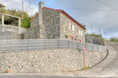a stone retaining wall next to a building at Ocean View Cottage a Home in Madeira in Fajã da Ovelha