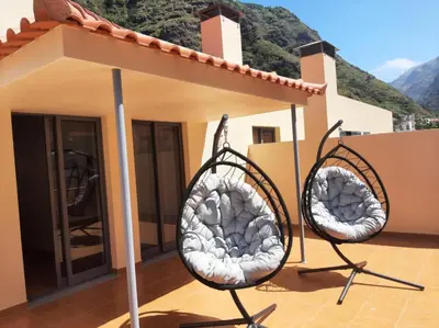 a row of benches on a sidewalk with palm trees at Paradise Valley Ribeira Brava in Ribeira Brava