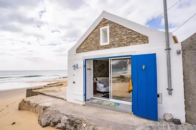 a tiny house with blue doors on the beach at Casa Neverland in Vila Baleira