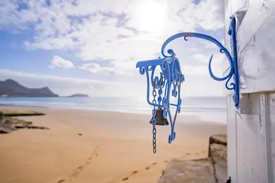 a blue door on a beach with the ocean in the background at Casa Neverland in Vila Baleira
