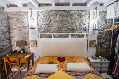 a bedroom with a bed and a table and a stone wall at Casa Neverland in Vila Baleira