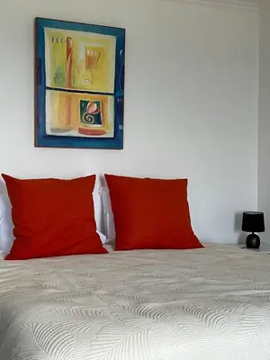 a bed with two red pillows and a painting on the wall at Taverna in São Jorge